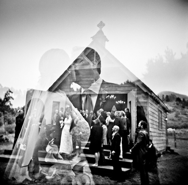 black and white photo - double exposure of bride and groom kissing and bride and groom with wedding party at ceremony in a small rustic church - photo by New Mexico based wedding photographers Twin Lens